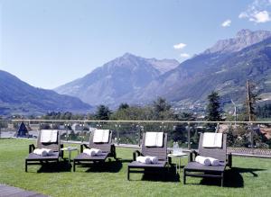 un gruppo di sedie sedute nell'erba con montagne sullo sfondo di Hotel Sittnerhof a Merano