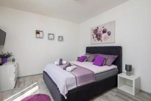 a bedroom with a large bed with purple pillows at Sky Way Apartments in Dugi Rat