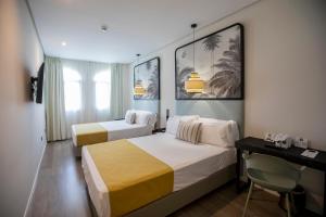 een hotelkamer met 2 bedden en een bureau bij Soho Boutique Puerto in El Puerto de Santa María