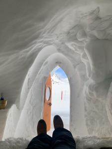 Due uomini seduti davanti a una porta in una scultura di neve di Village Igloo Les Arcs ad Arc 2000