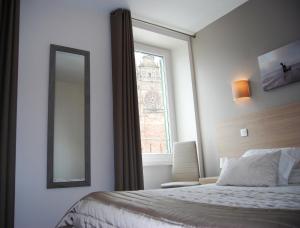 A bed or beds in a room at Logis Hôtel du Midi - Rodez Centre-Ville