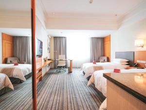 Ramada Plaza Shanghai Pudong Airport في شانغهاي: غرفه فندقيه ثلاث اسره ومكتب