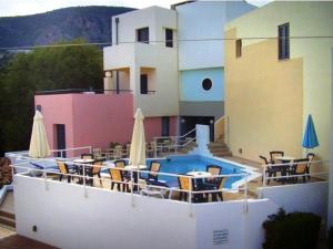 un edificio con piscina, sillas y sombrillas en Blue Sky Hotel Apartments, en Tolo