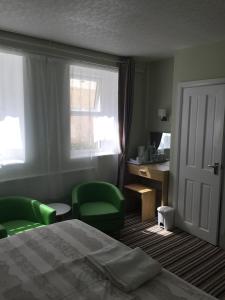 - une chambre avec un lit, 2 chaises vertes et un bureau dans l'établissement Tregonholme Guesthouse, à Bournemouth