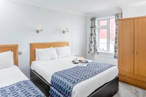 een hotelkamer met 2 bedden en een raam bij The Kilbirnie Hotel in Newquay