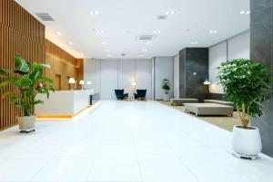 an office lobby with potted plants on the floor at Ramada Encore by Wyndham CheonAn in Cheonan