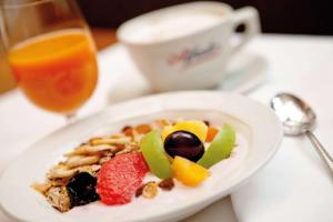 un plato de comida con fruta en una mesa con una bebida en Vienna House by Wyndham Thüringer Hof Eisenach, en Eisenach