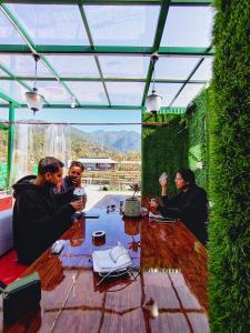 um grupo de pessoas sentadas à mesa com bebidas em Raahi Stay, Landing site Bir - Stay & Cafe em Bir