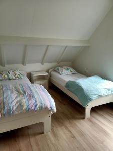 Habitación con 2 camas, paredes blancas y suelo de madera. en Vakantiehuis Mastdreef, en Breda