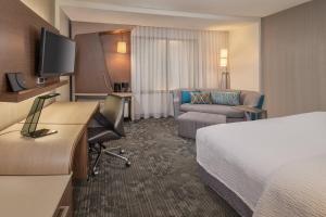 Courtyard by Marriott St. Louis West County في سانت لويس: غرفة الفندق بسرير ومكتب واريكة