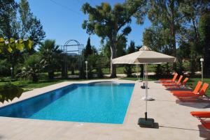 a swimming pool with orange chairs and an umbrella at Villa Vivere in Corfu Town