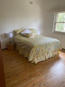 - une chambre avec un lit doté d'une couette et d'une fenêtre dans l'établissement Gracious 1930s Art Deco House, à Gosford