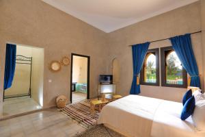 a bedroom with a large bed with blue curtains at Atlas Widan in Marrakech