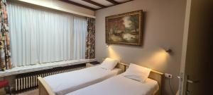 two beds in a room with a picture on the wall at Alliance Hotel Ieper Centrum in Ypres