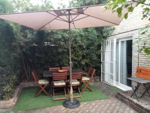 a table and chairs under an umbrella on a patio at Dormir entre limones, Casa de invitados en vivienda familiar in Dos Hermanas