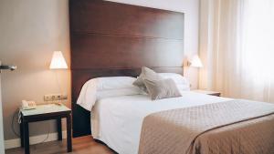 a bedroom with a large bed with a wooden headboard at Vértice Sevilla Aljarafe in Bormujos