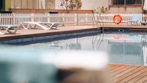 a swimming pool with two chairs and an orange life preserver at Vértice Sevilla Aljarafe in Bormujos