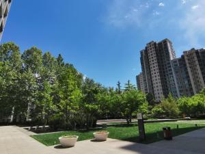 un parco con alberi ed edifici sullo sfondo di Beijing Yasmine Seasons Park Apartment Hotel a Pechino