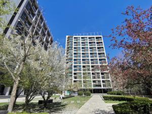 un edificio alto con alberi di fronte di Beijing Yasmine Seasons Park Apartment Hotel a Pechino