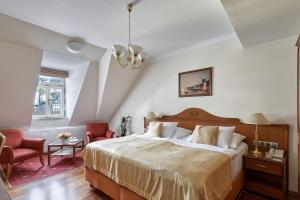 um quarto com uma cama grande e 2 cadeiras em Hotel Romance em Karlovy Vary