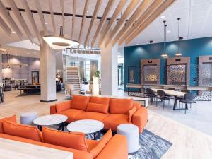 een lobby met een bank en tafels en stoelen bij Novotel Liverpool Paddington Village in Liverpool