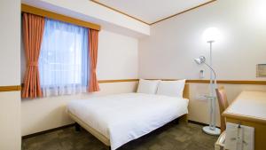 a bedroom with a white bed and a window at Toyoko Inn Morioka eki Minami guchi Ekimae in Morioka