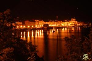 une ville la nuit avec des lumières sur l'eau dans l'établissement Hotel Casa Arizzoli, à Cannobio