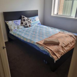 a bed with a blanket and pillows on it at Home stay in Wyndham Vale