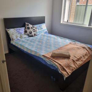 a small bed with a blanket and pillows on it at Home stay in Wyndham Vale