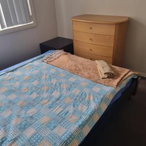 a bed with a quilt and a dresser in a bedroom at Home stay in Wyndham Vale