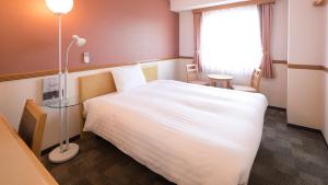 Un dormitorio con una gran cama blanca y una lámpara en Toyoko Inn Himeji eki Shinkansen Minami guchi, en Himeji