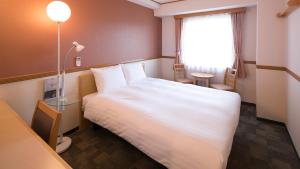 a hotel room with a white bed and a window at Toyoko Inn Ichinoseki Ekimae in Ichinoseki