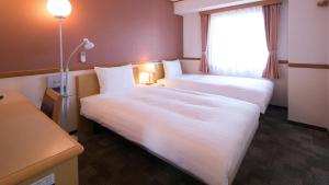 a hotel room with two beds and a window at Toyoko Inn Ichinoseki Ekimae in Ichinoseki