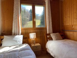 1 Schlafzimmer mit 2 Betten und einem Fenster in der Unterkunft Chalet Savoyard avec Cheminée et Parking à Samoëns - FR-1-624-80 in Samoëns