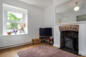 een woonkamer met een open haard en een televisie bij Lavender Terrace in Llandudno