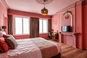 een slaapkamer met roze muren en een bed en een televisie bij Boutique hotel Sies in Watervliet