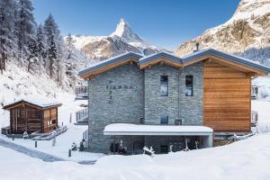 ein Gebäude im Schnee mit Bergen im Hintergrund in der Unterkunft Piccola Fiamma by Pizzo Fiamma in Zermatt