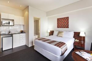 une chambre d'hôtel avec un lit et une cuisine dans l'établissement Macleay Hotel, à Sydney