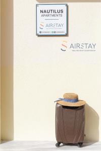 einem braunen Koffer vor einem Schild in der Unterkunft Nautilus Apartments Airport by Airstay in Artemida