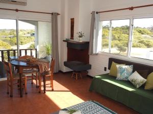 een woonkamer met een tafel, een bank en ramen bij El Diablo Chic Colonial in Punta Del Diablo