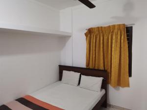 een bed in een kamer met een geel gordijn bij Nallur Holidays Inn in Jaffna