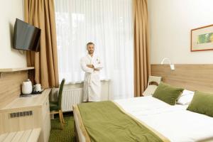 a man standing in a hotel room with his arms crossed at Medical SPA "Eglės sanatorija" Standard Druskininkai in Druskininkai