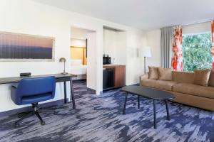 ein Hotelzimmer mit einem Sofa, einem Schreibtisch und einem Zimmer in der Unterkunft Fairfield Inn and Suites by Marriott San Jose Airport in San Jose