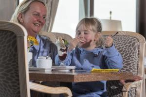 een man en een klein meisje eten aan een tafel bij Maritim Strandhotel Travemünde in Travemünde