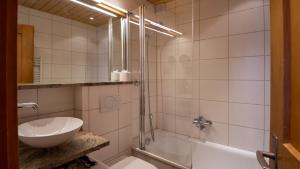 a bathroom with a shower and a sink and a tub at Stachelbeere OG in Fiesch