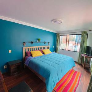 Schlafzimmer mit einem Bett mit blauer Wand in der Unterkunft The Rooftop Bolivia in La Paz