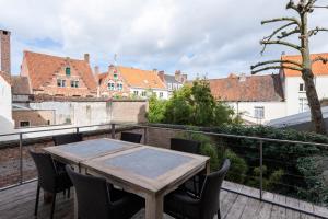 uma mesa de madeira numa varanda com cadeiras em Dukes' Apartments Grand Place - by Dukes' Hotel Collection em Bruges