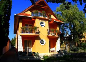 um edifício amarelo com varandas e plantas nele em Járja Panzió em Hajdúszoboszló