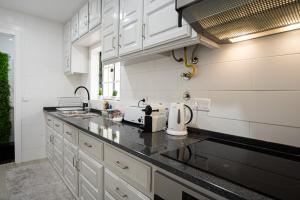 a kitchen with white cabinets and a black counter top at Casa Fonte Nova in Nazaré