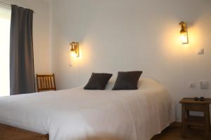 1 dormitorio con 1 cama blanca y 2 almohadas en Sunrise Apartmento Ribeira d'Ilhas Ericeira, en Ericeira